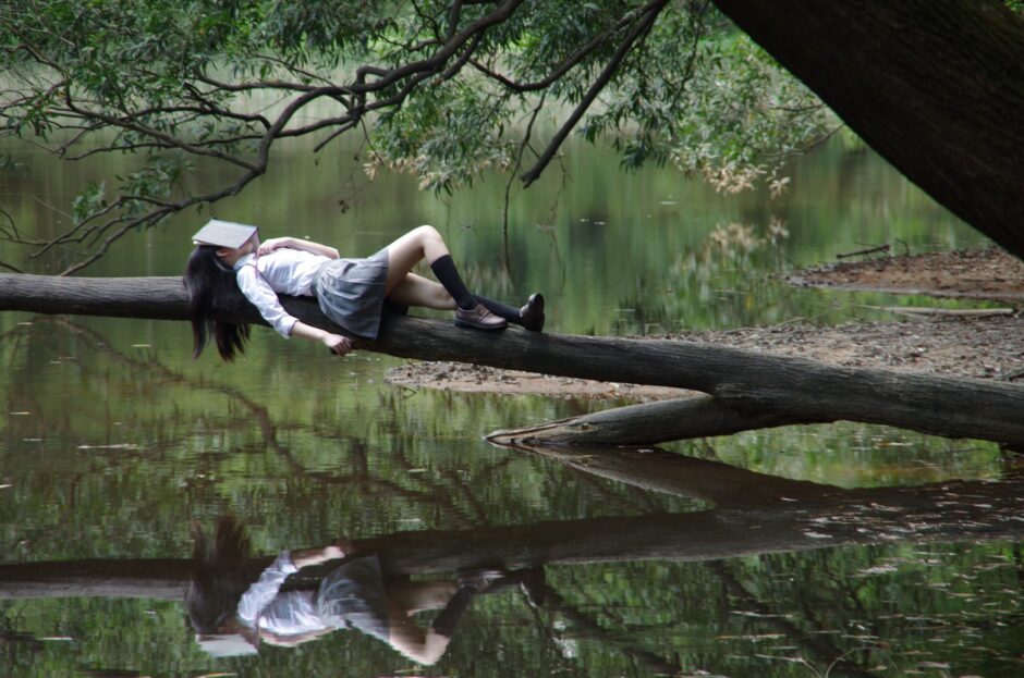 Girl asleep on tree branch with book over her face represents accessing dreams and intuition.
