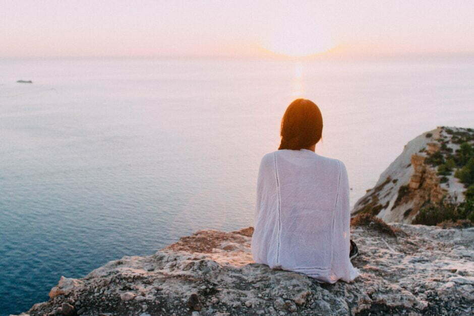 Woman meditating by the sea as a symbol of psycho-spiritual healing